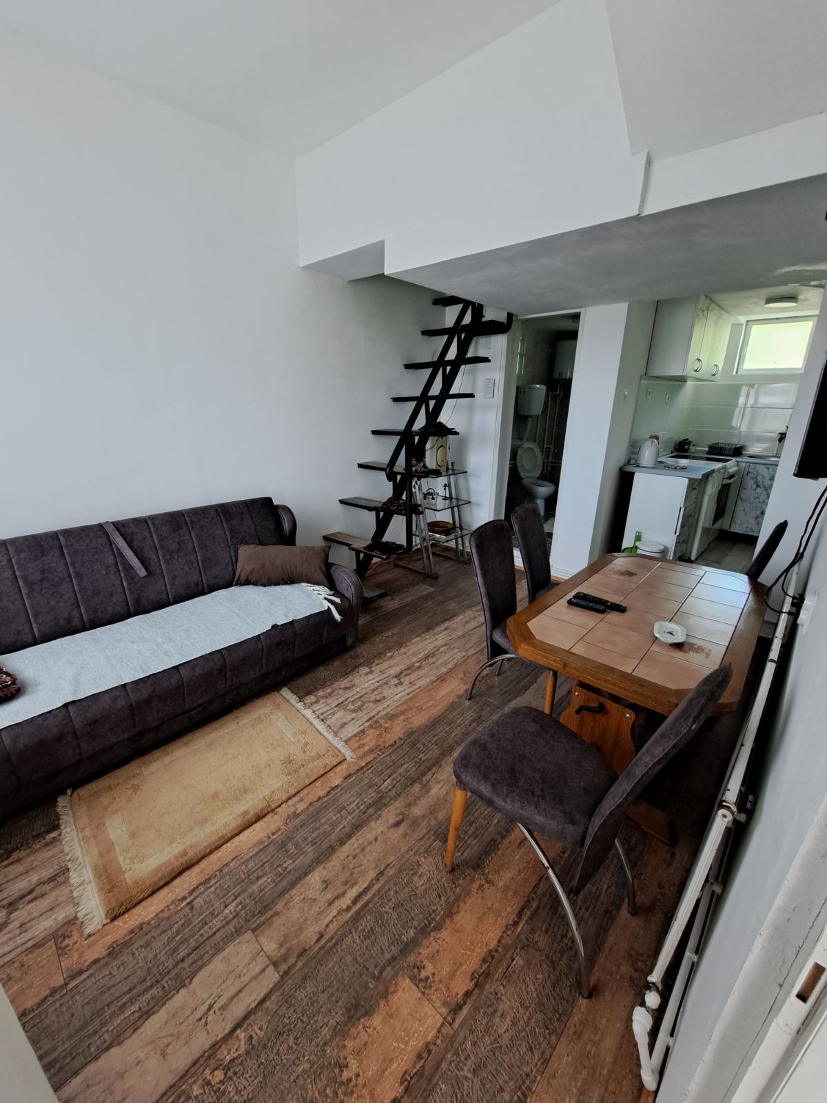 Đokić Apartman2 Dnevna soba sa jednim ležajem, trpezariskim stolom i četri stolice i stepenice za sprat